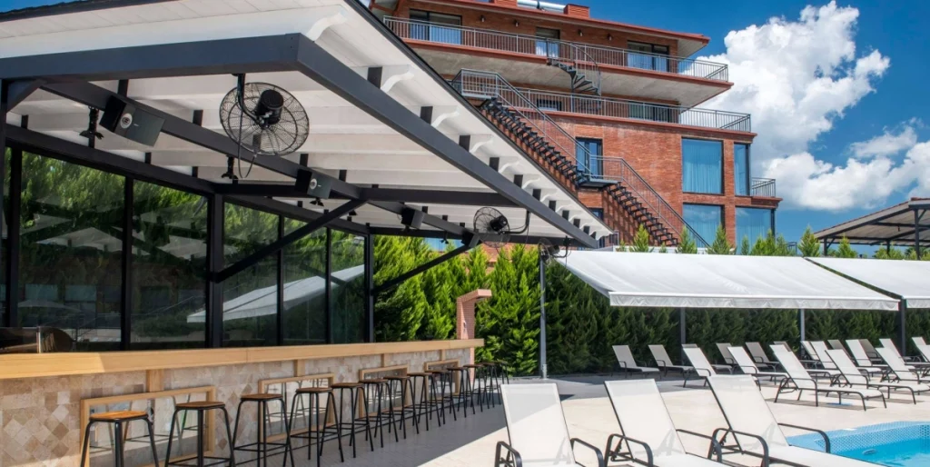 Pool Cafe — Hotel building exterior viewed from the pool deck with loungers and a bar.