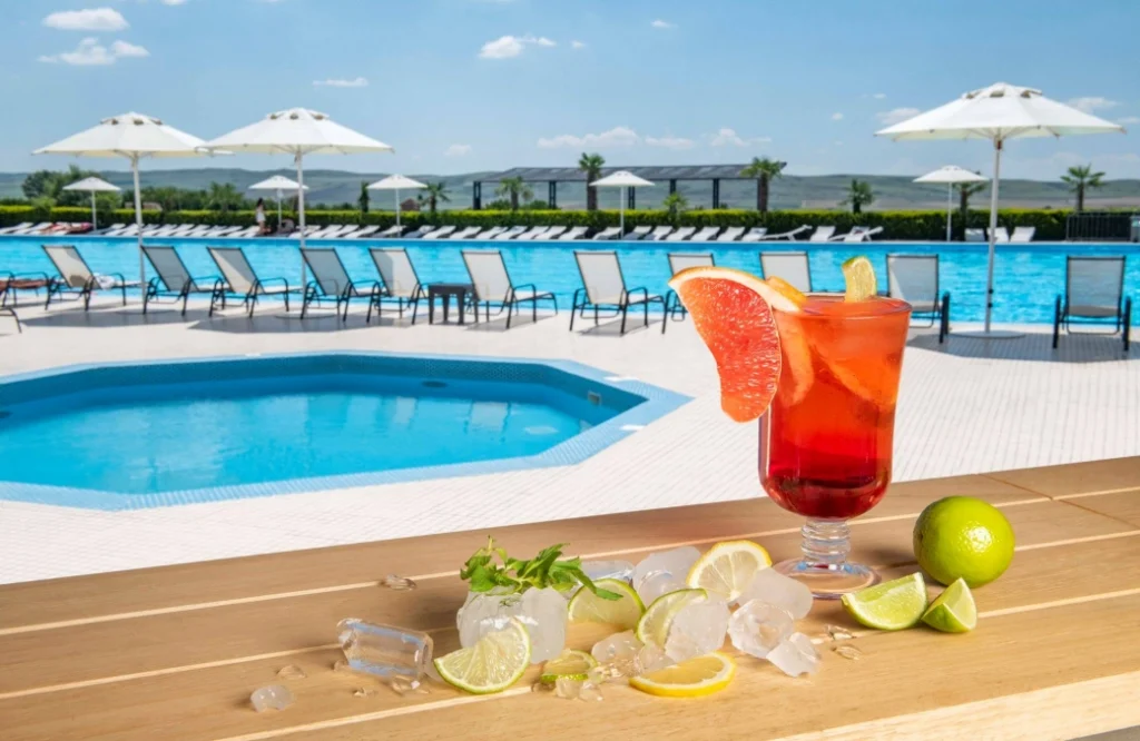 Pool Cafe — Pool deck with loungers, umbrellas, and a garnished cocktail on a table.