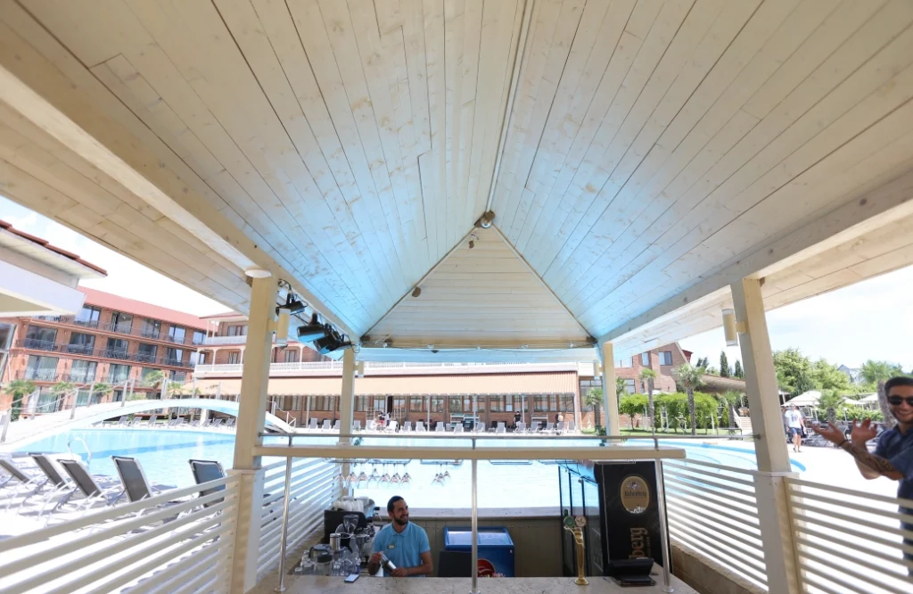 Pool Cafe — Wide view of the pool area and hotel buildings from a covered poolside bar.