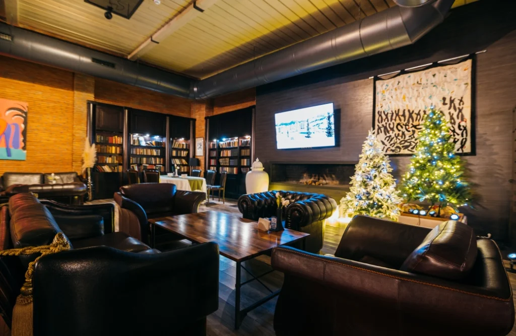 Restaurant & Lounge — Cozy lounge area with leather sofas, bookshelves, and a lit fireplace.