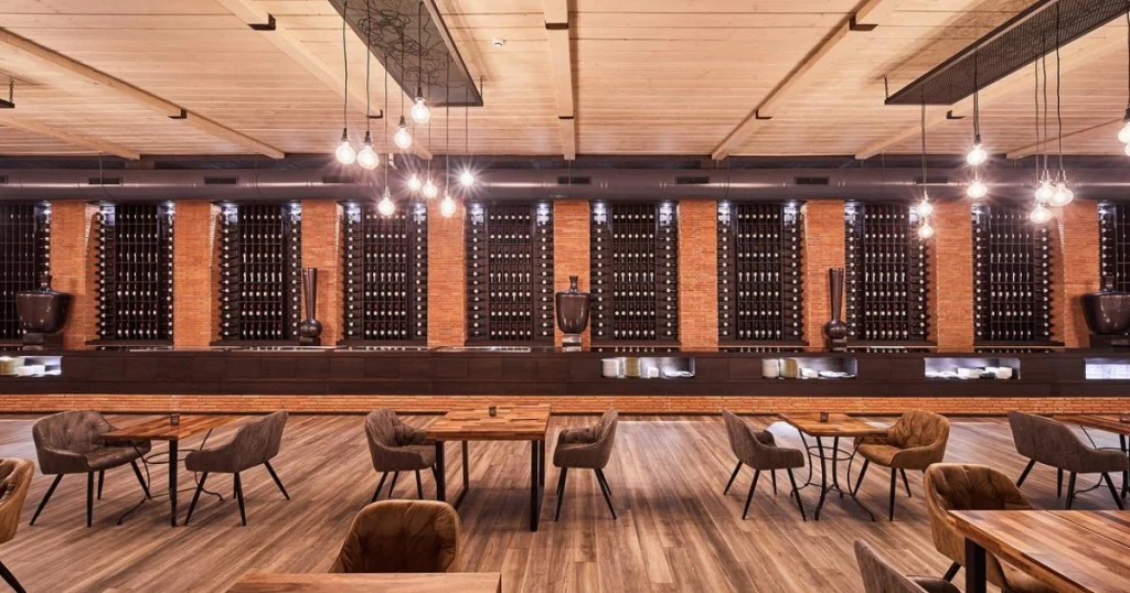 Restaurant & Lounge — Industrial-style restaurant interior with wine wall, wooden tables, and hanging bulb lighting.