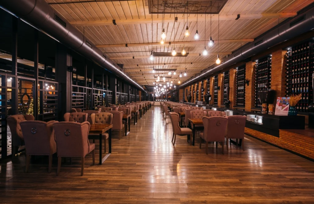 Restaurant & Lounge — Elegant indoor restaurant with wine wall, hanging lights, and wooden dining tables.