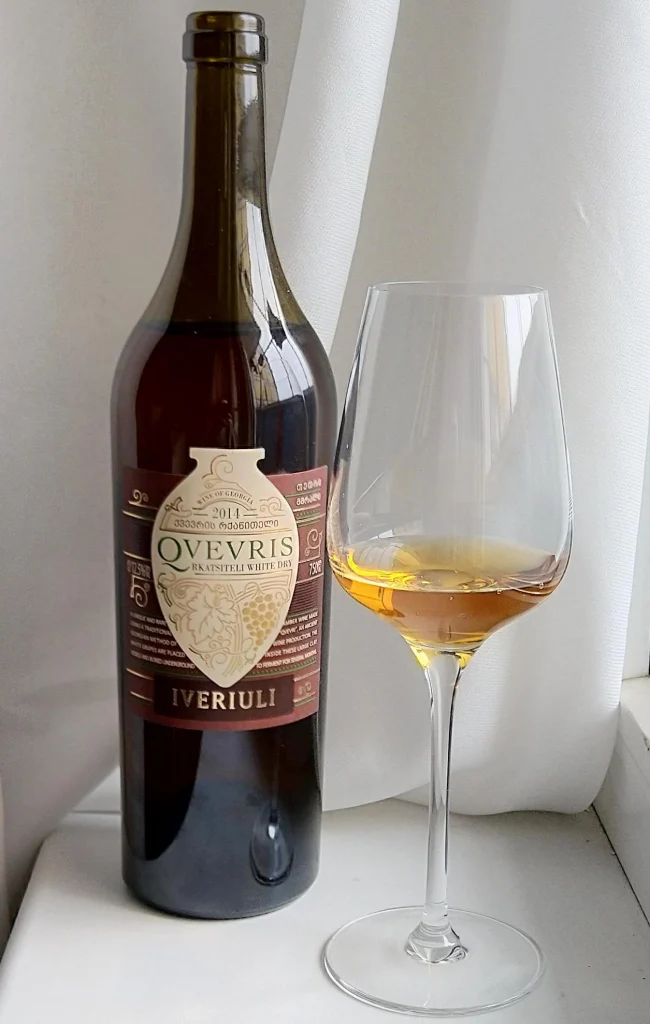 A bottle and glass of amber qvevri wine made from the Rkatsiteli grape, Georgia's signature style.
