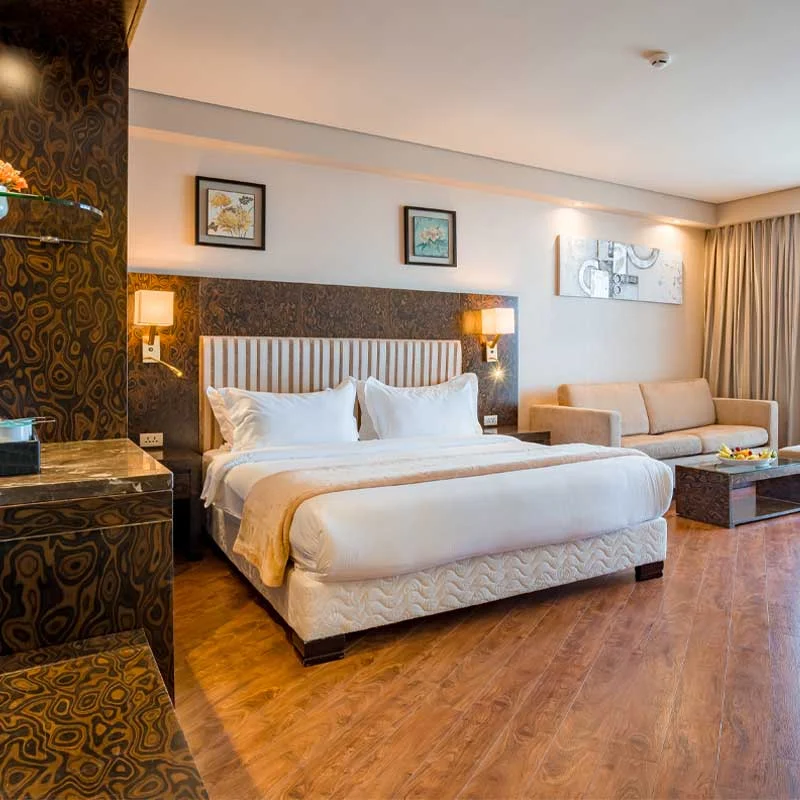 Sky Lounge — просторный номер отеля с кроватью king-size, диваном и акцентной стеной из узорчатого мрамора.