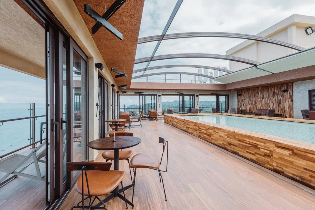 Sky Lounge — бассейн-инфинити на крыше с деревянным настилом, зонами отдыха и сдвижной стеклянной крышей с видом на океан.