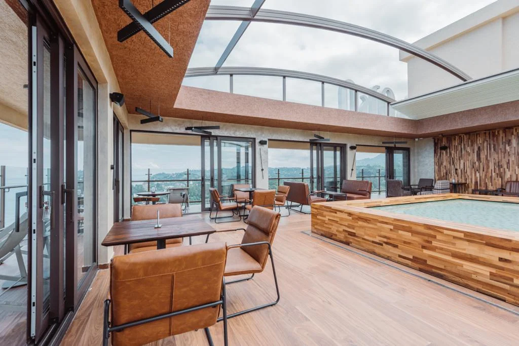 Sky Lounge — зона отдыха у бассейна на крыше со сдвижной стеклянной крышей и видом на океан.