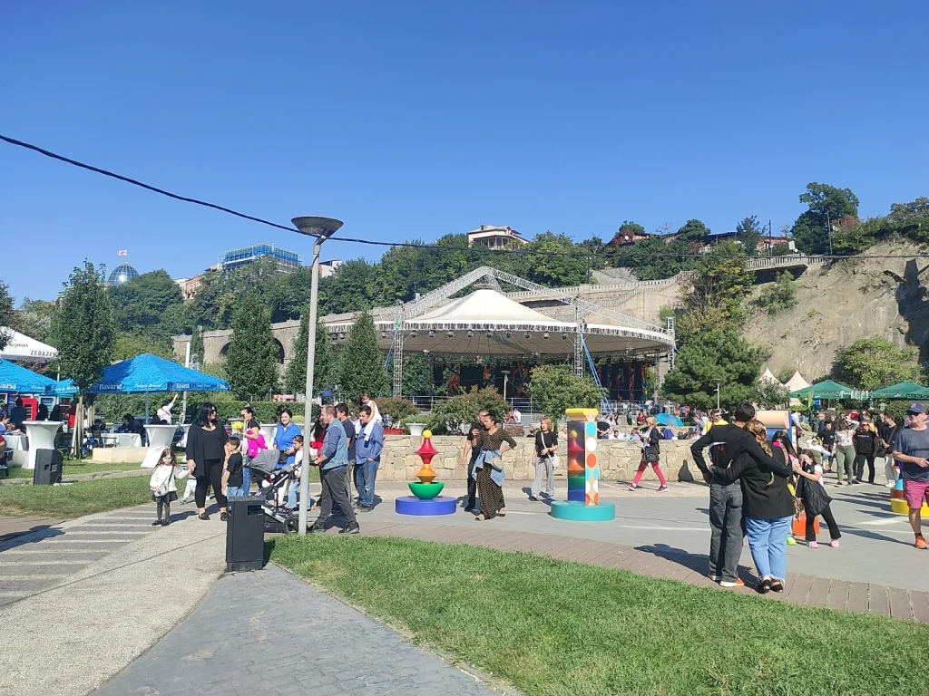 Visitors mingle near the main stage and playful sculptures at Tbilisoba in Rike Park.