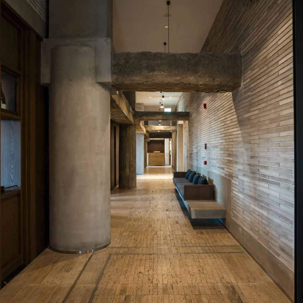 Telegraph Hotel — Hotel corridor with concrete columns, beams, and a tiled accent wall.