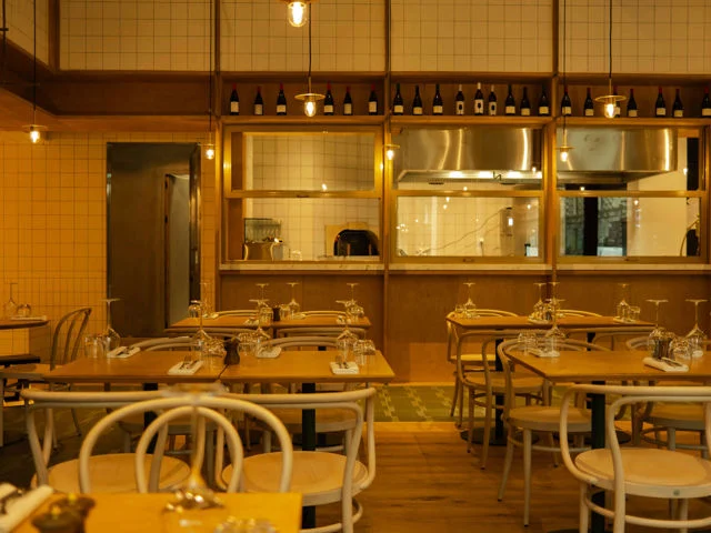Telegraph Hotel — Restaurant dining room with wooden tables, bentwood chairs, and an open kitchen.
