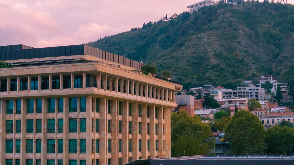 The Grill — Exterior view of the building with hillside cityscape in the background.